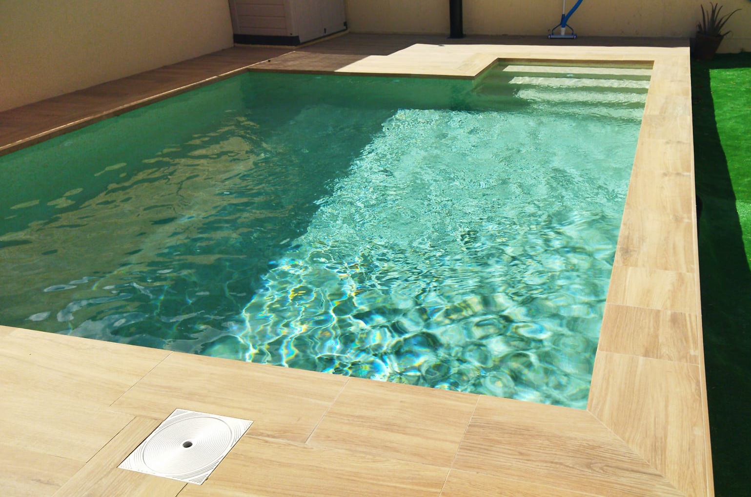 Family-friendly swimming pool design with shallow lounging area and sunbeds.