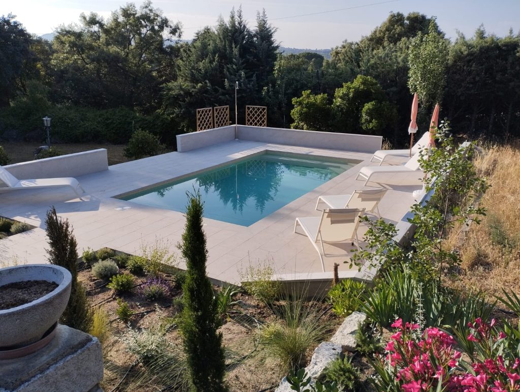 A tranquil garden scene with a swimming pool and a lawn chair positioned nearby for leisure.